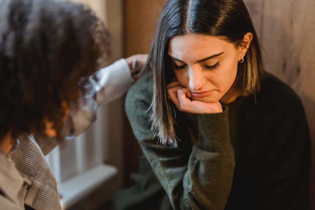 A young lady confiding in a friend about what's worrying her.